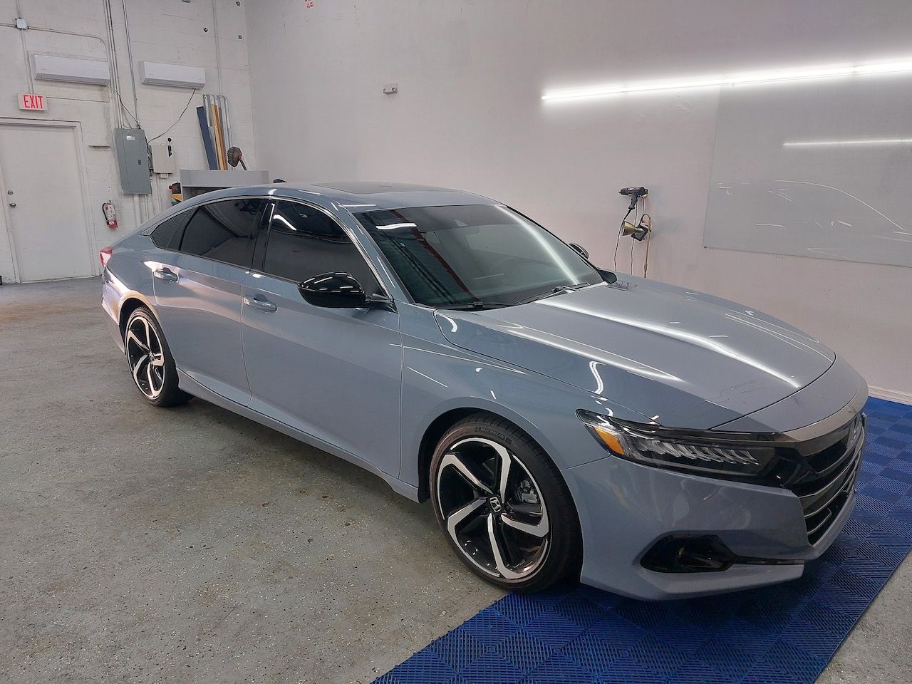A grey honda accord is parked in a garage.