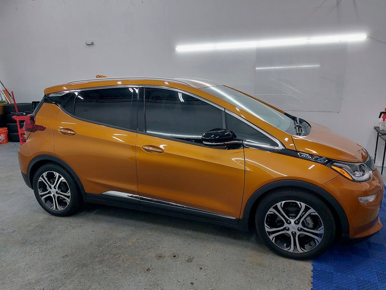 A small orange car is parked in a garage.