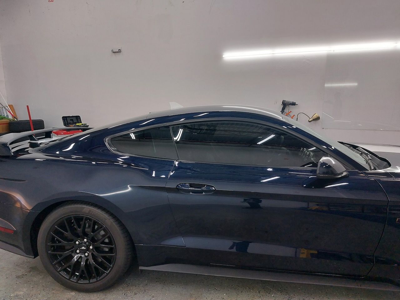 A blue ford mustang is parked in a garage.