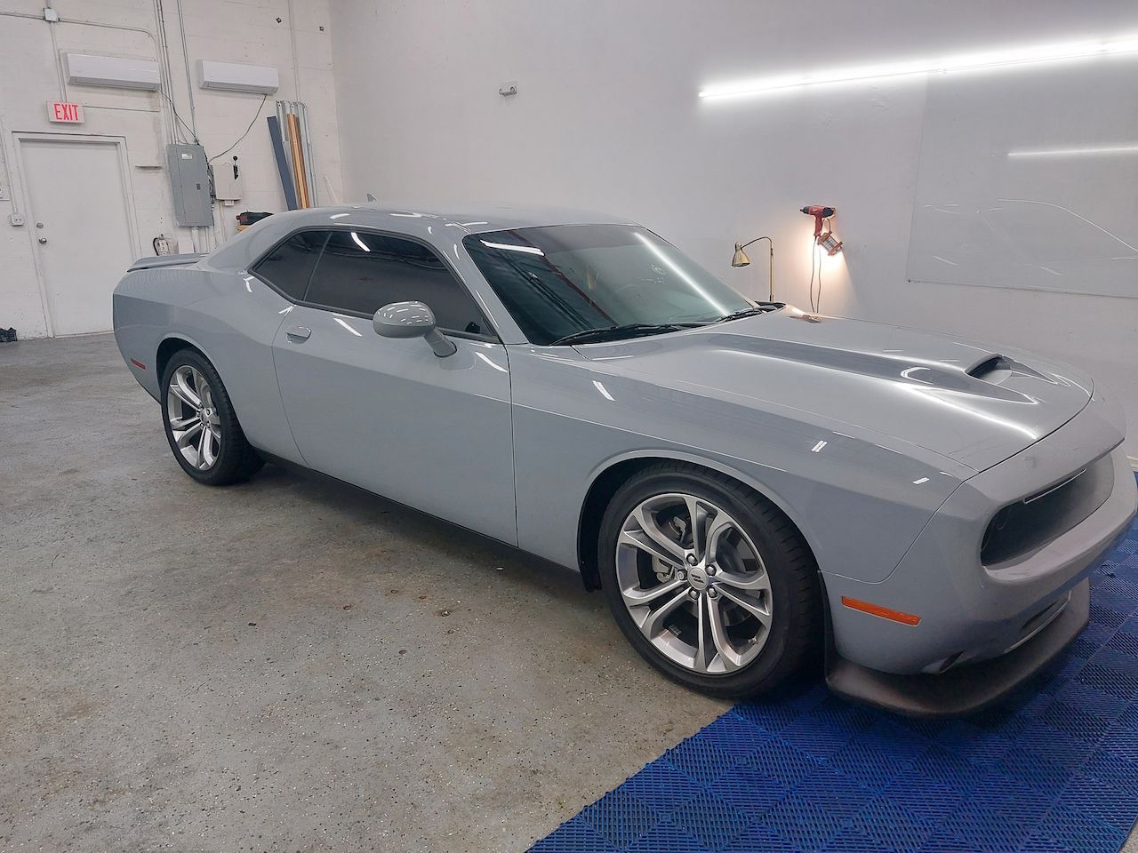 A gray dodge challenger is parked in a garage.