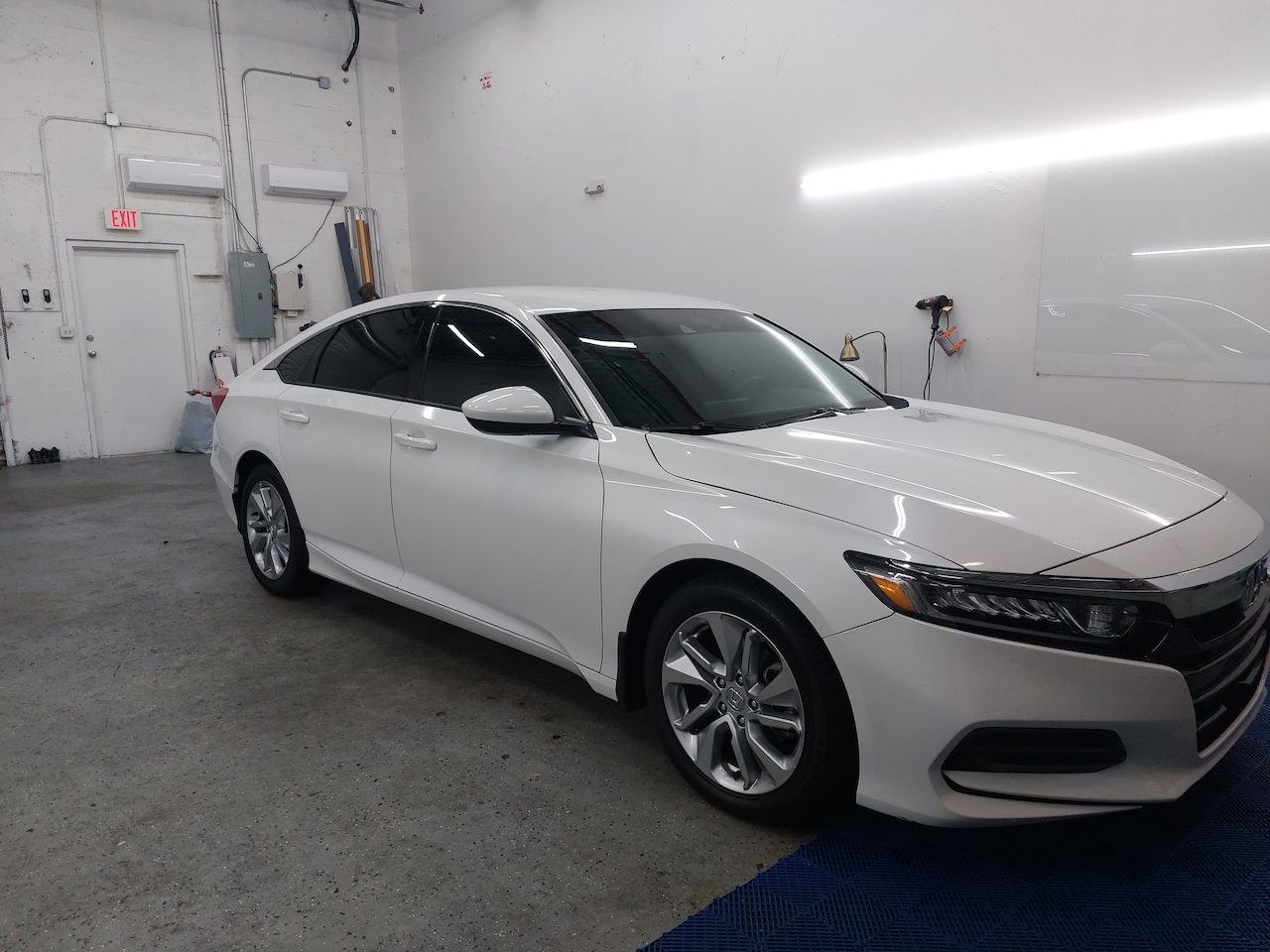 A white honda accord is parked in a garage.