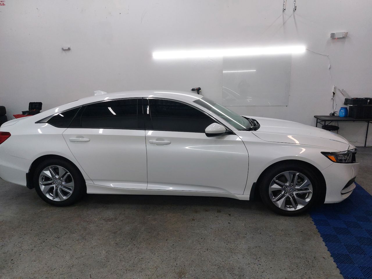 A white honda accord is parked in a garage.