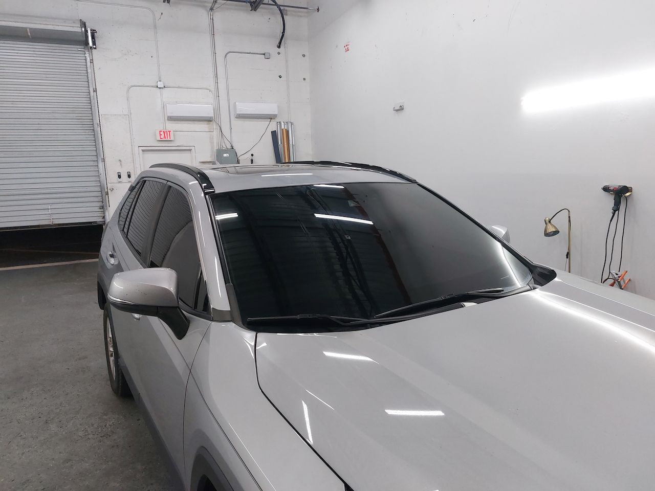 A white car with black windows is parked in a garage.