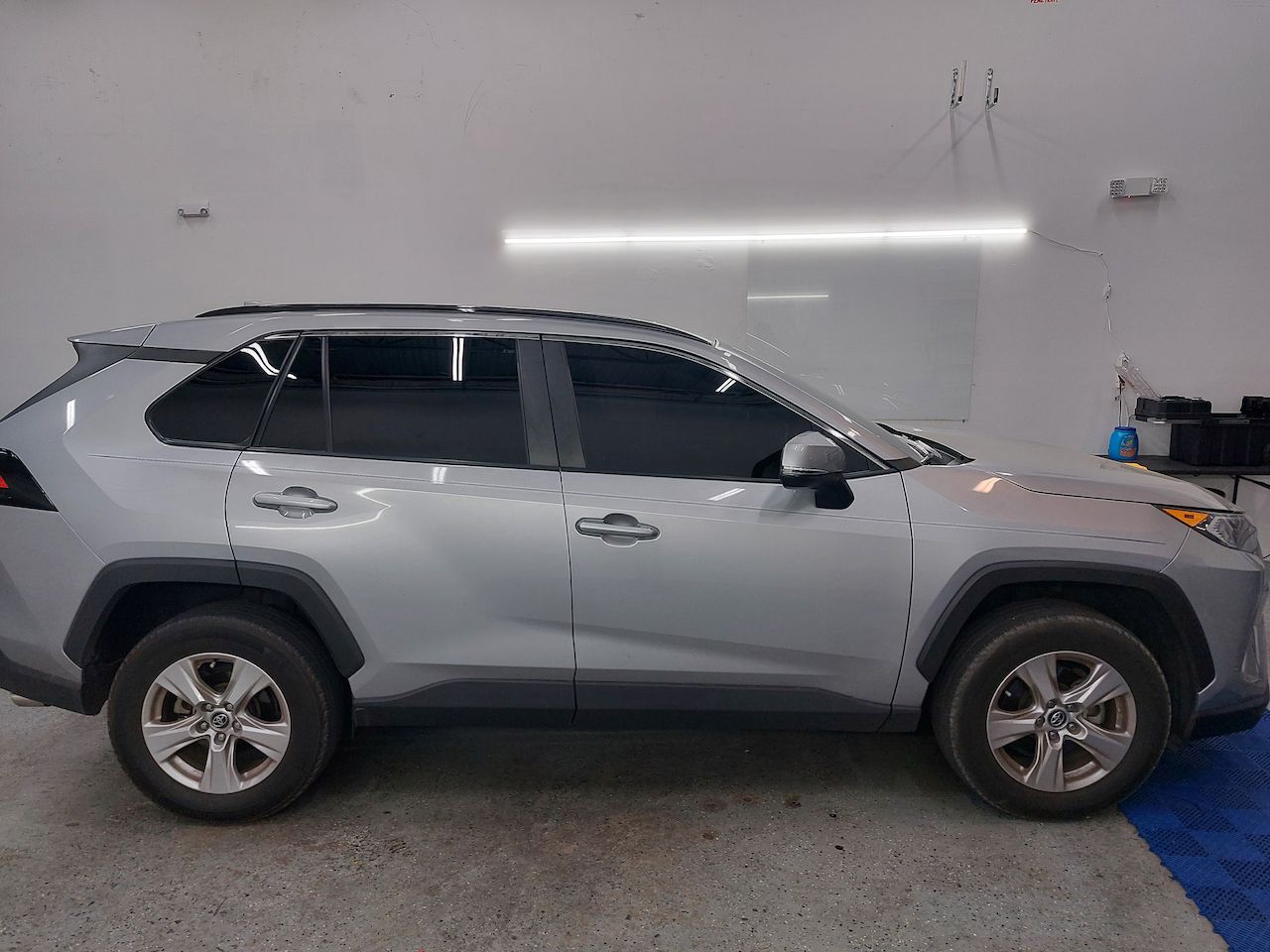 A silver toyota rav4 is parked in a garage.