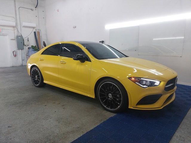 A yellow mercedes benz cla class is parked in a garage.
