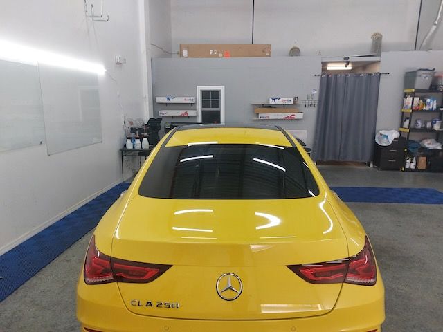 A yellow mercedes cla 250 is parked in a garage