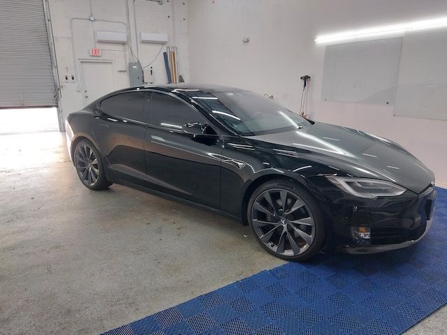 A black tesla model s is parked in a garage.