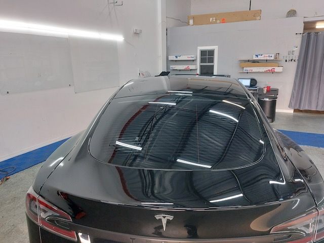A black tesla model s is parked in a garage