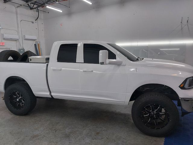 A white truck with black wheels is parked in a garage.