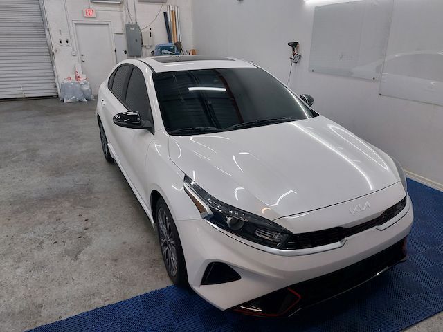 A white car is parked on a blue mat in a garage.