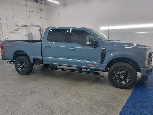 A blue pickup truck is parked in a garage.