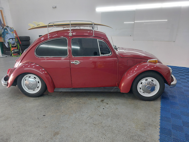 A red beetle with a surfboard on top of it