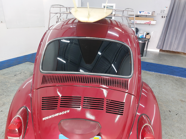 A red car with a surfboard on top of it