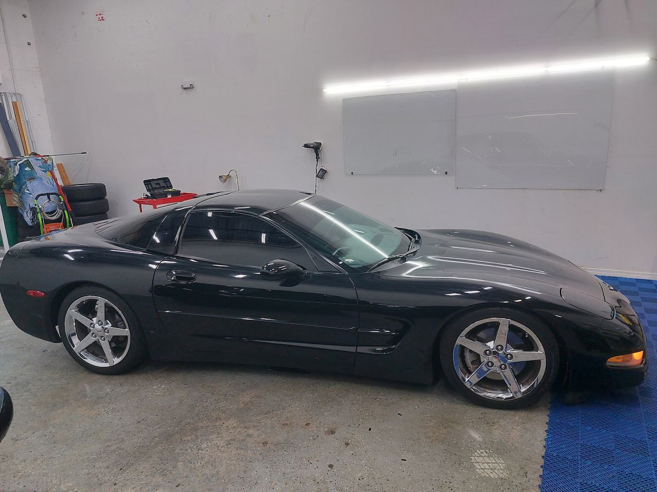 A black corvette is parked in a garage.