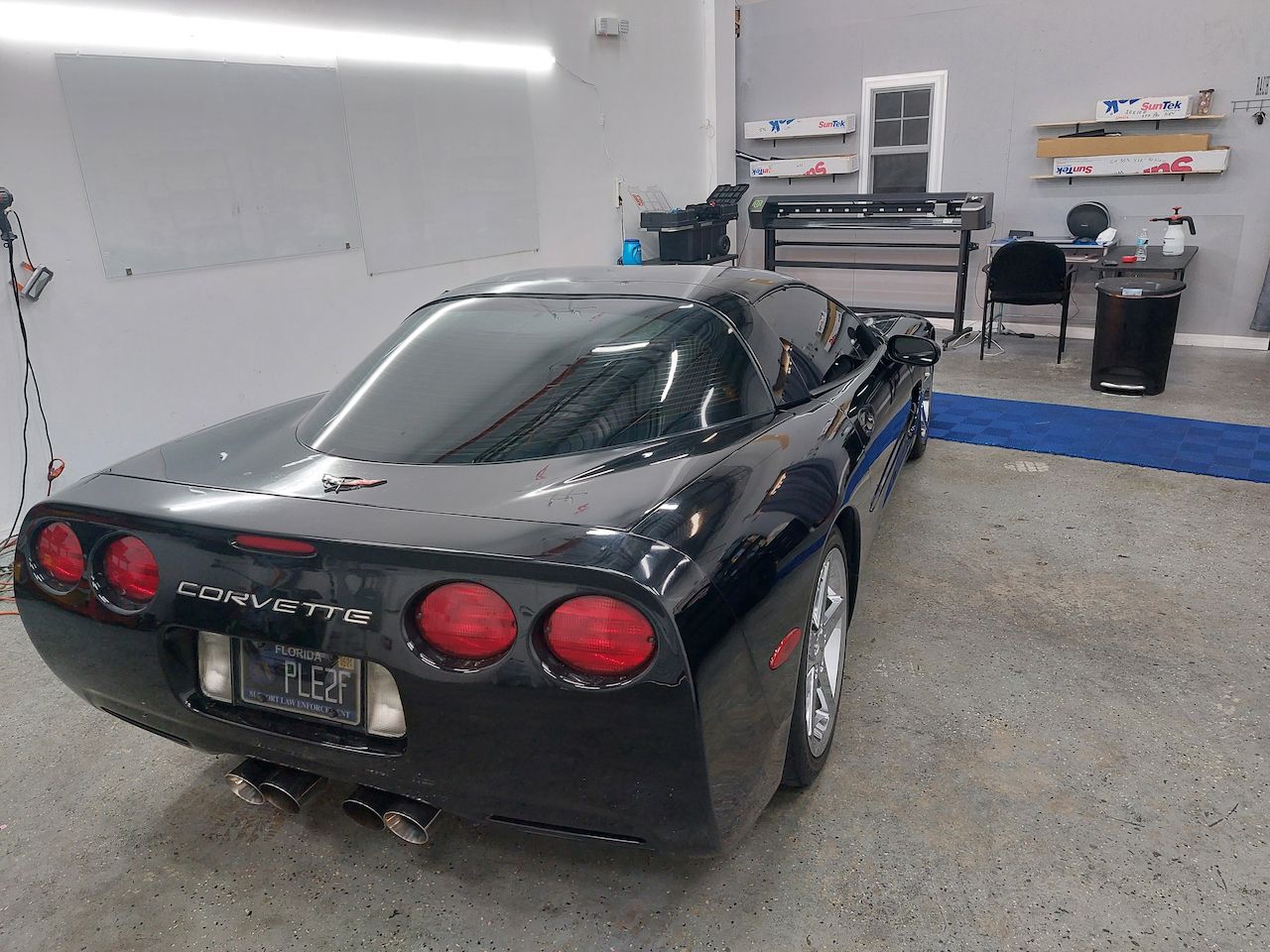 A black corvette is parked in a garage