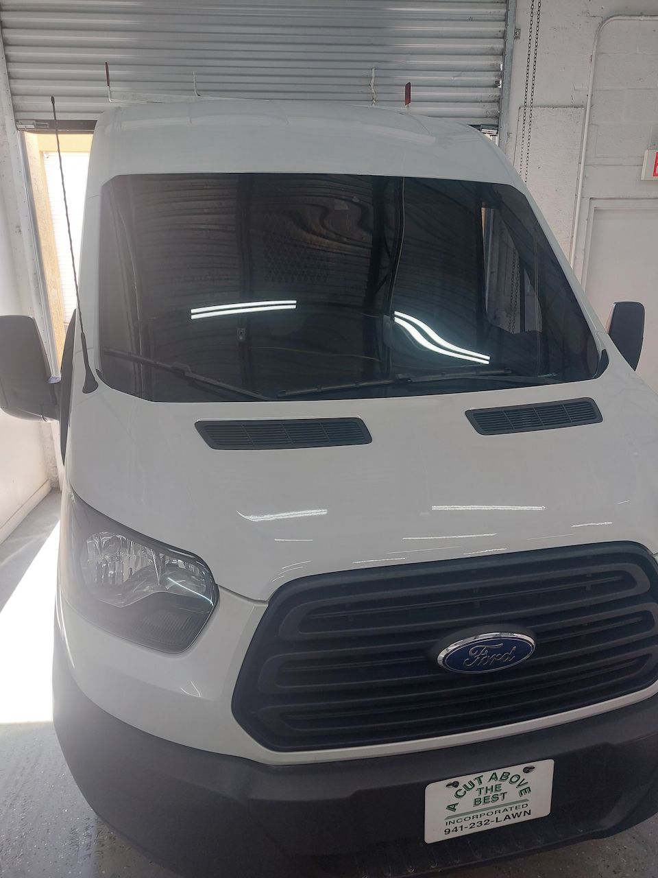 A white ford transit van is parked in a garage.