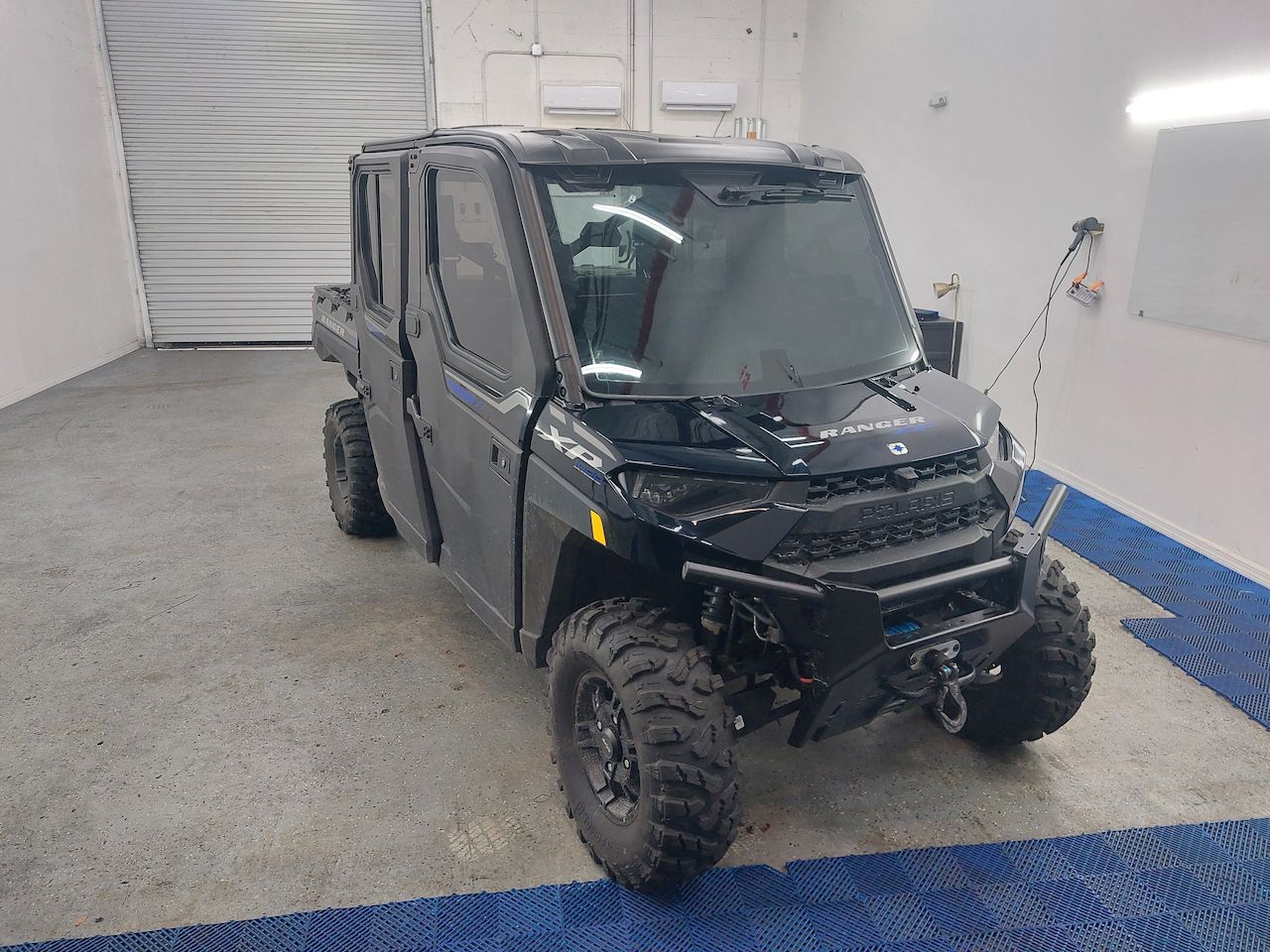 A black polaris ranger is parked in a garage.