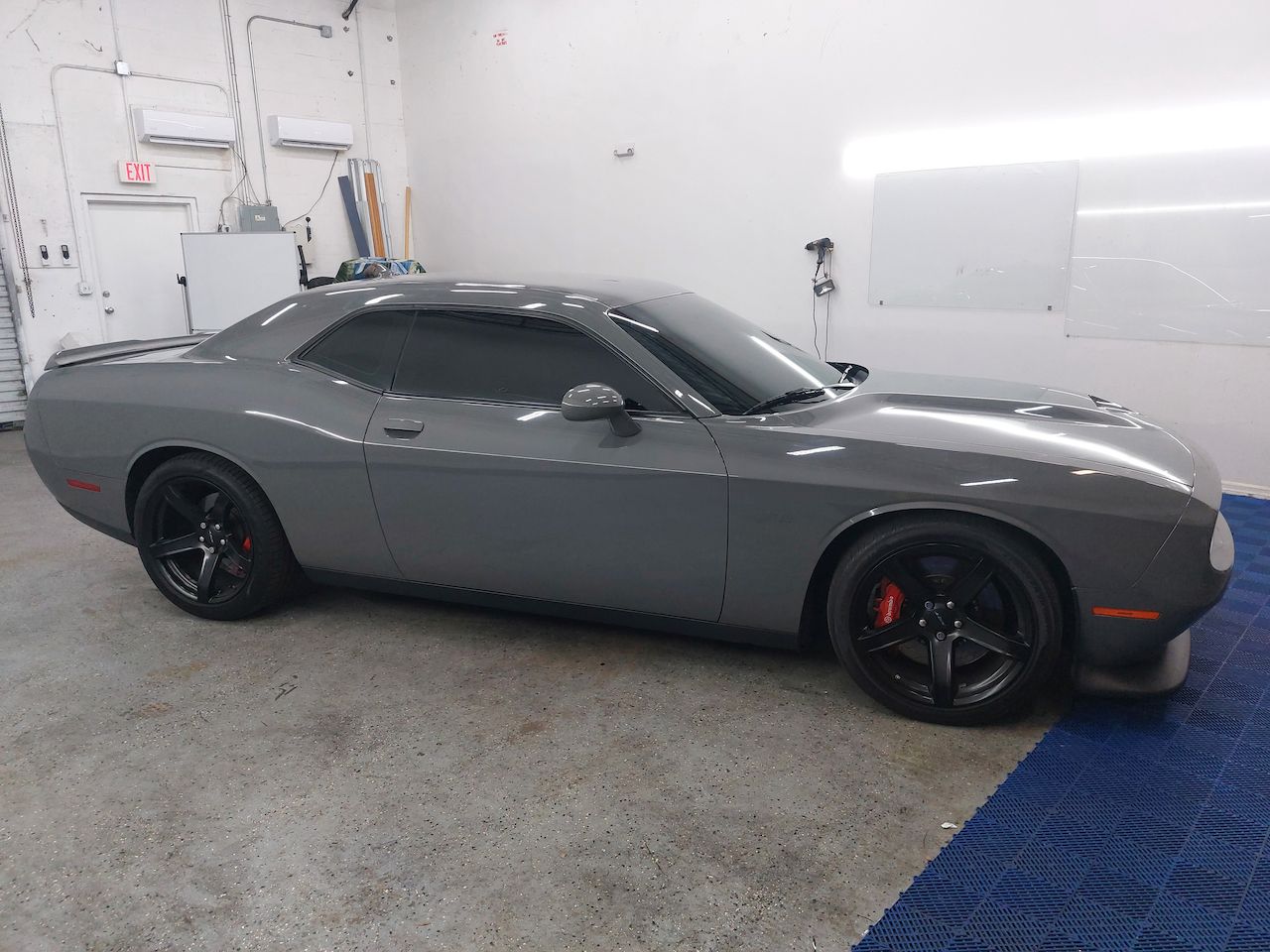 A gray dodge challenger is parked in a garage.