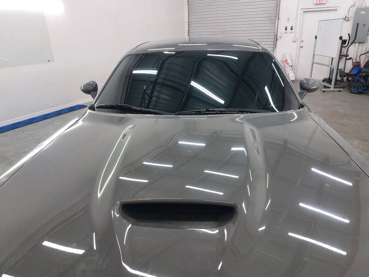 A gray car is parked in a garage with the hood up
