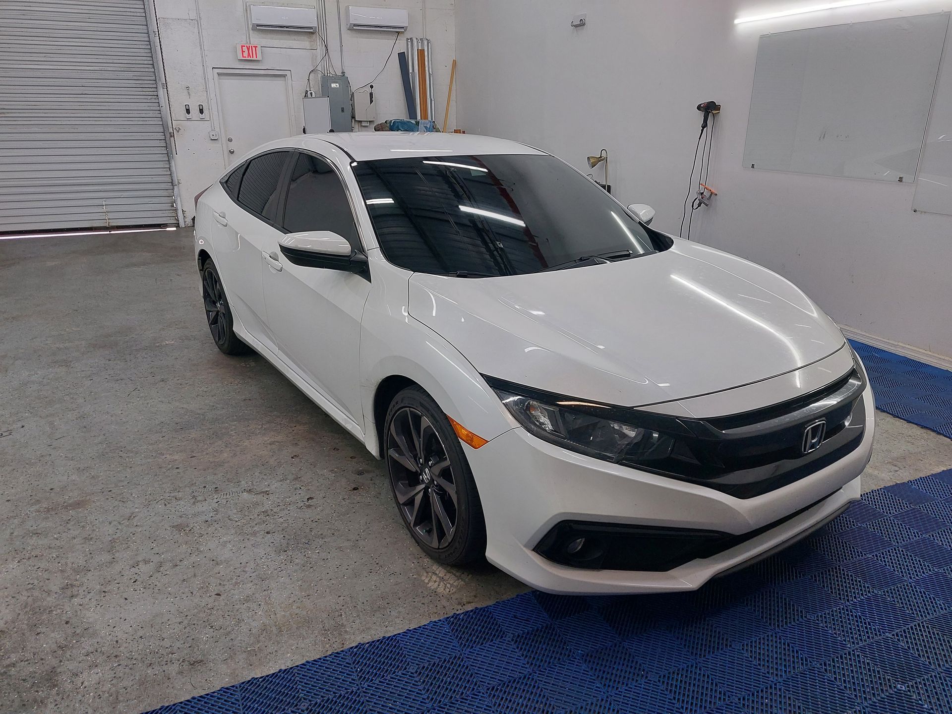 A white honda civic is parked in a garage.