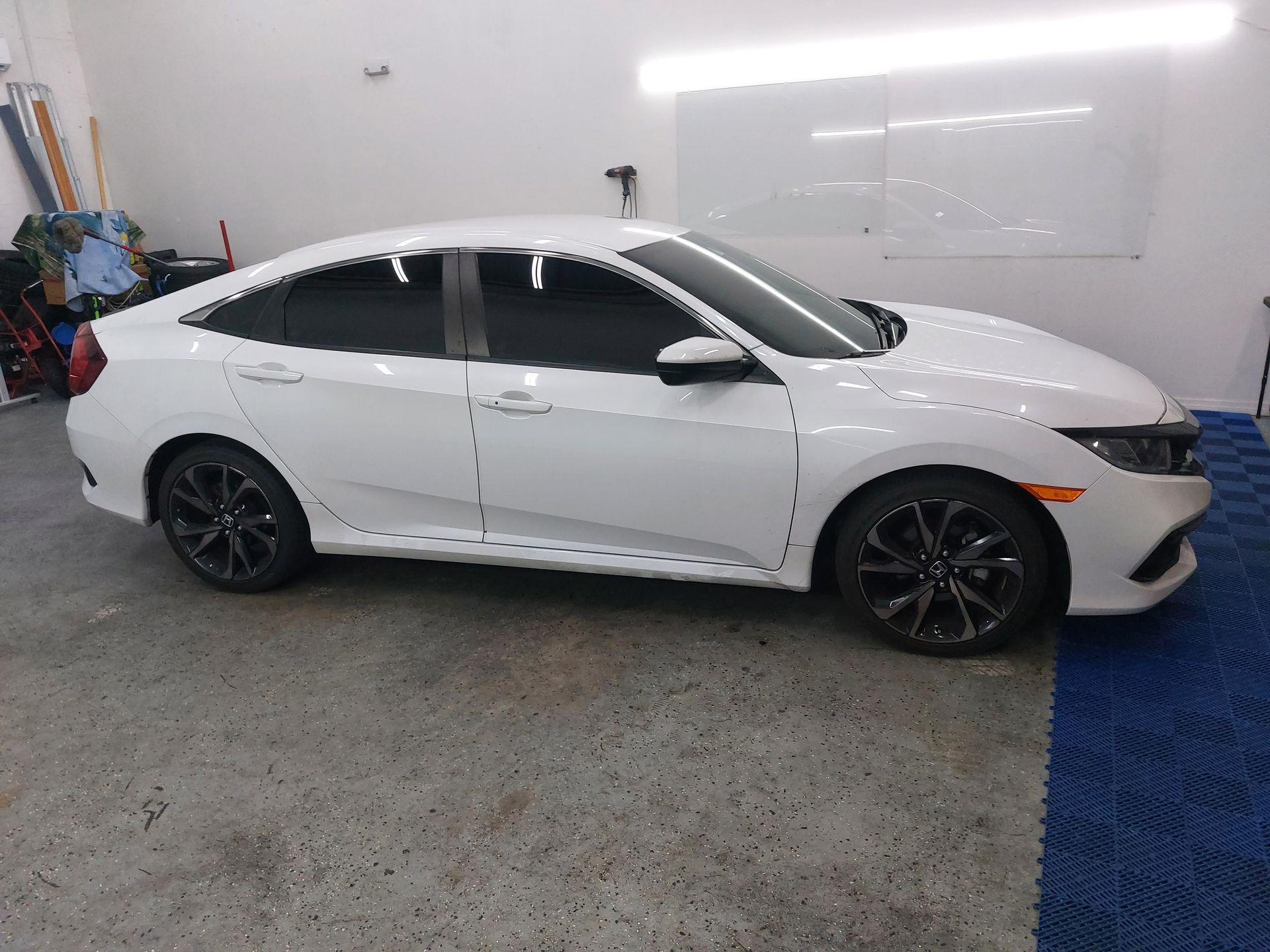 A white honda civic is parked in a garage.