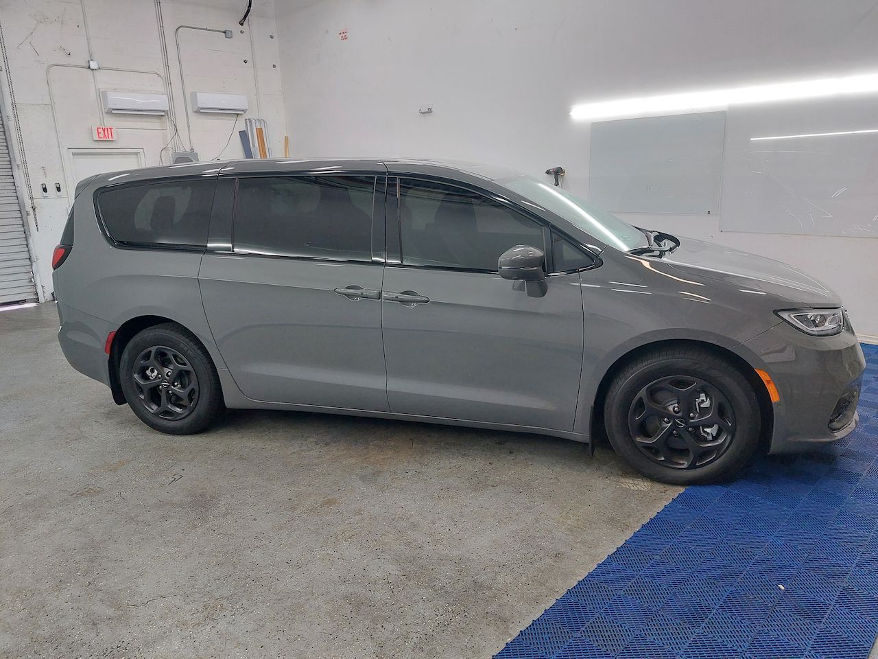 A gray minivan is parked in a garage.