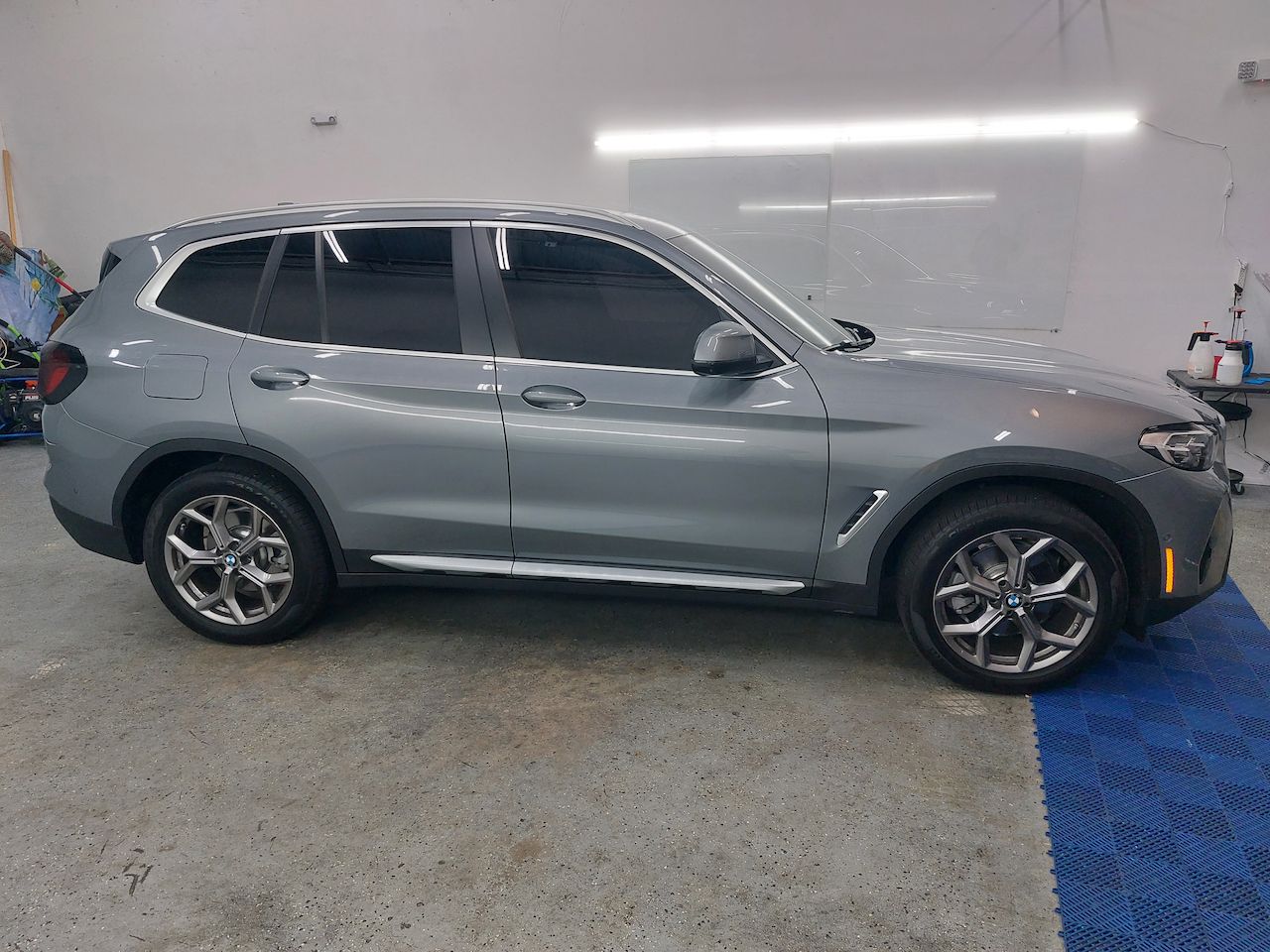 A gray bmw x3 is parked in a garage.