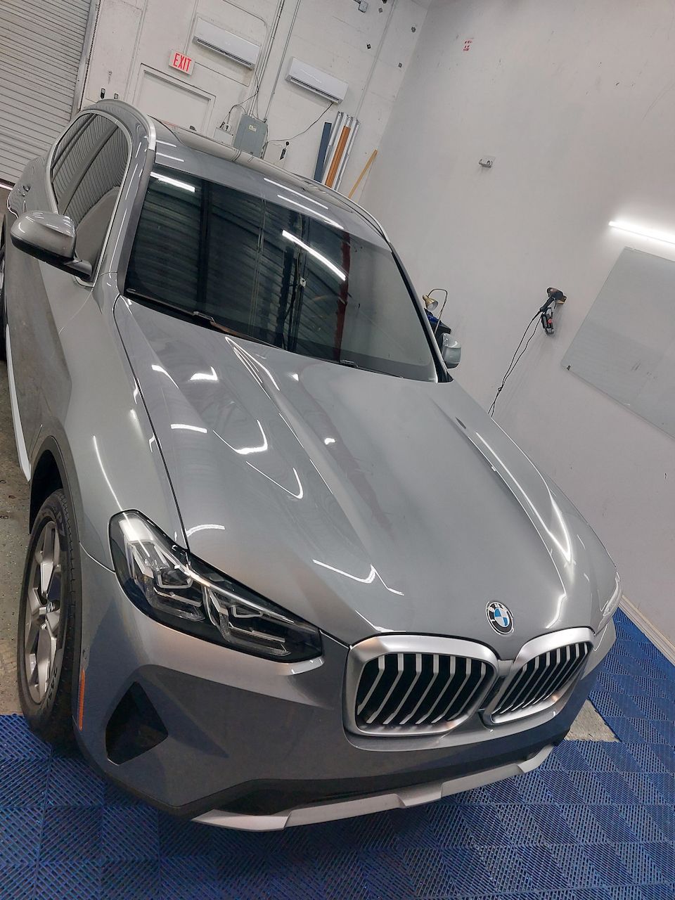 A silver bmw x3 is parked in a garage.