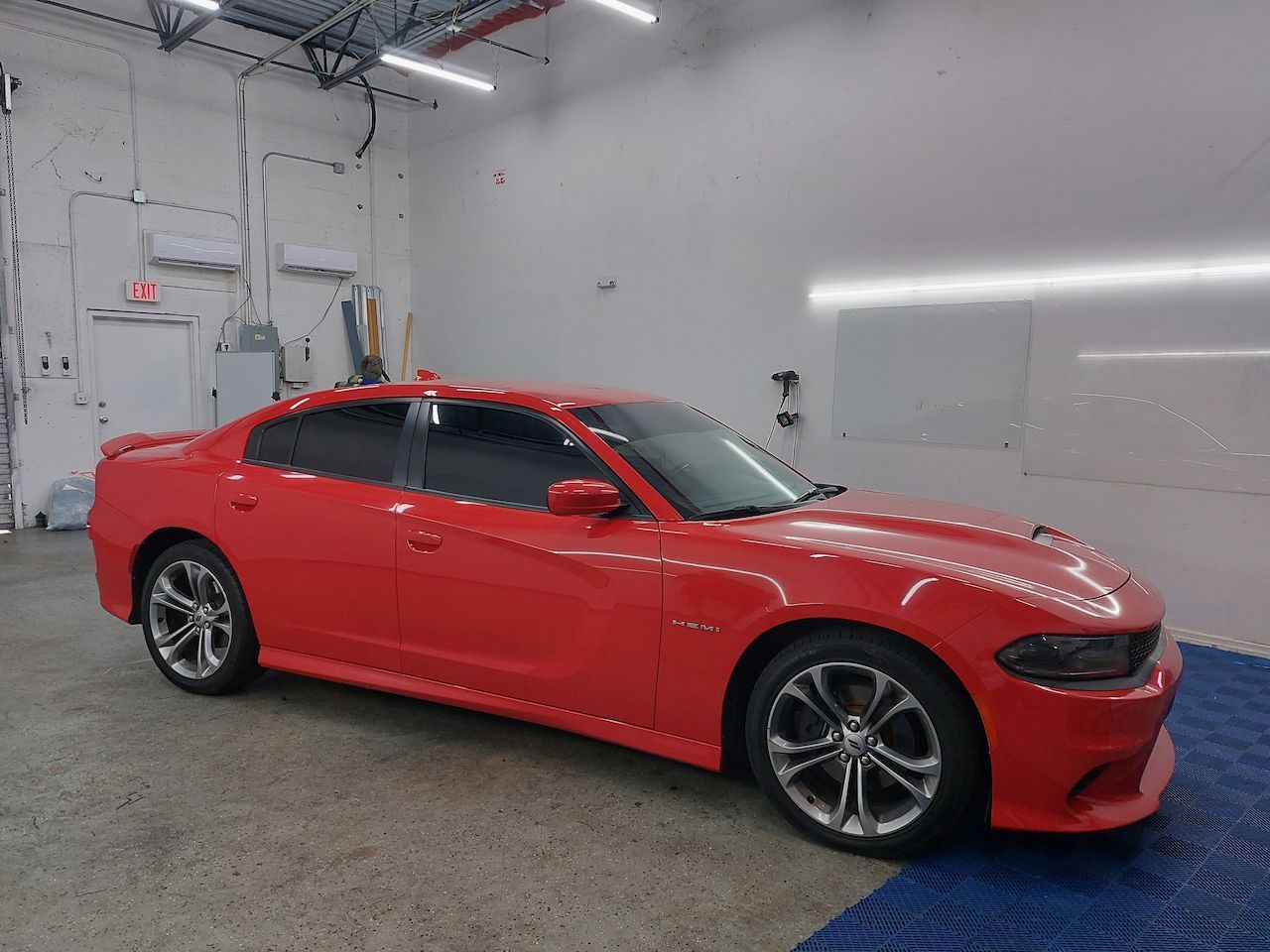 A red dodge charger is parked in a garage.