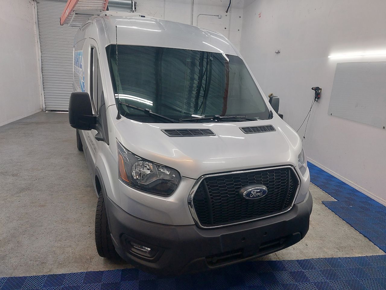 A white ford transit van is parked in a garage.