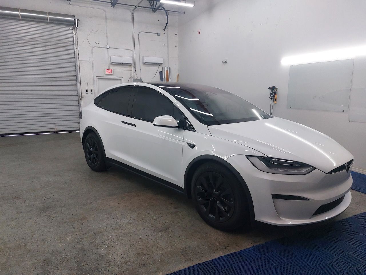 A white tesla model x is parked in a garage.