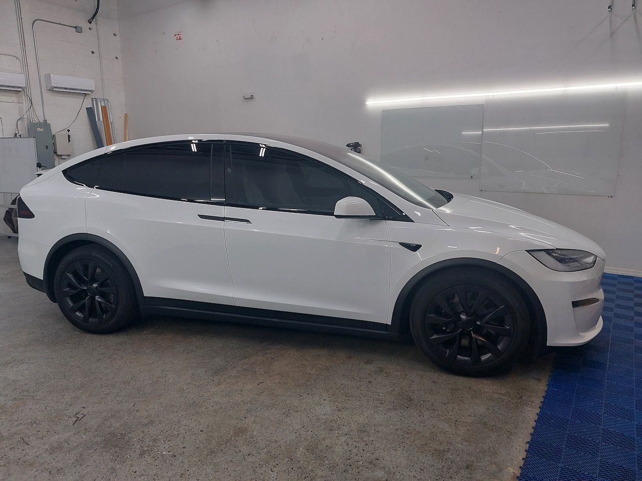 A white tesla model x is parked in a garage.