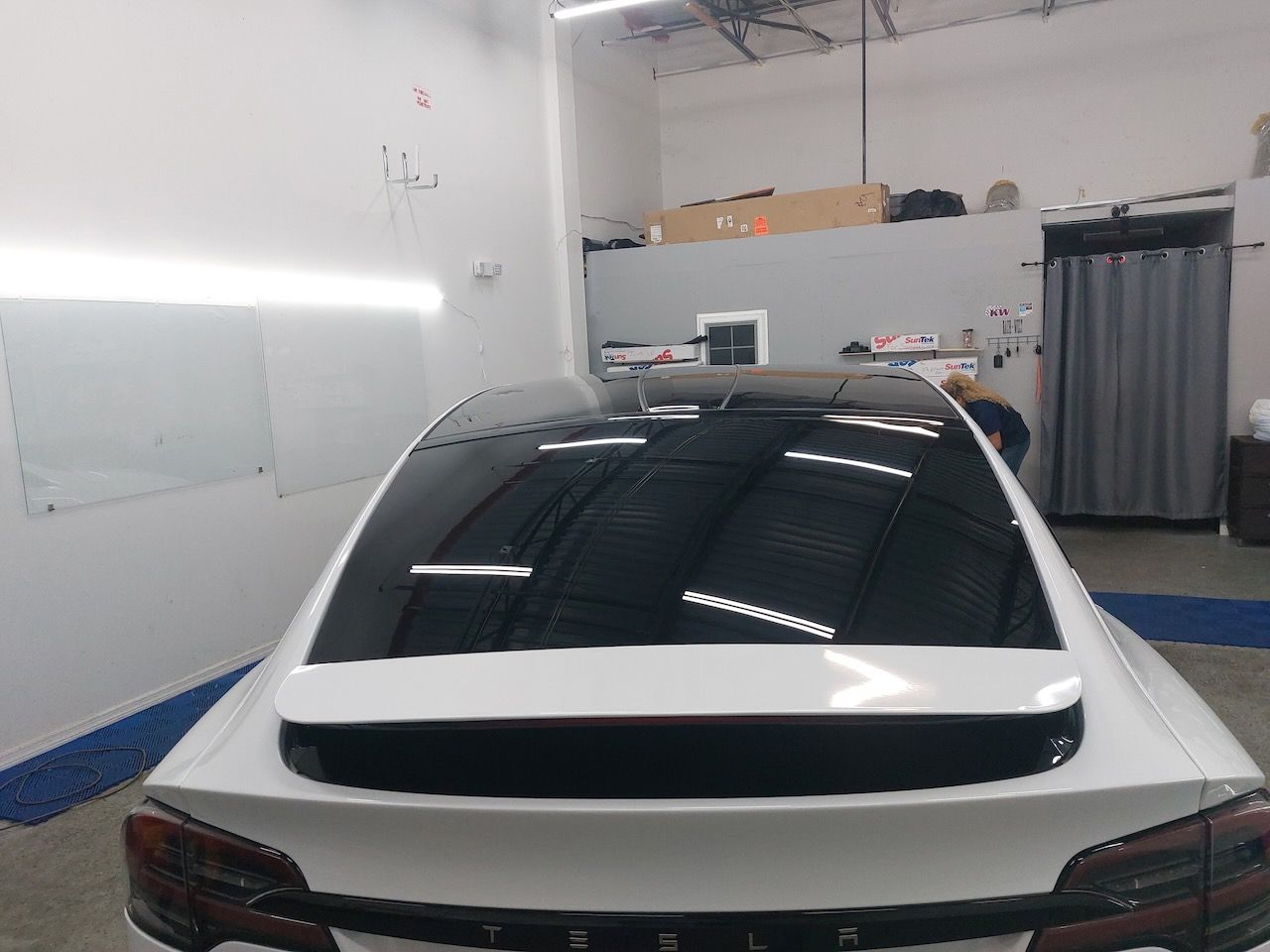 A white car with a black roof is parked in a garage.
