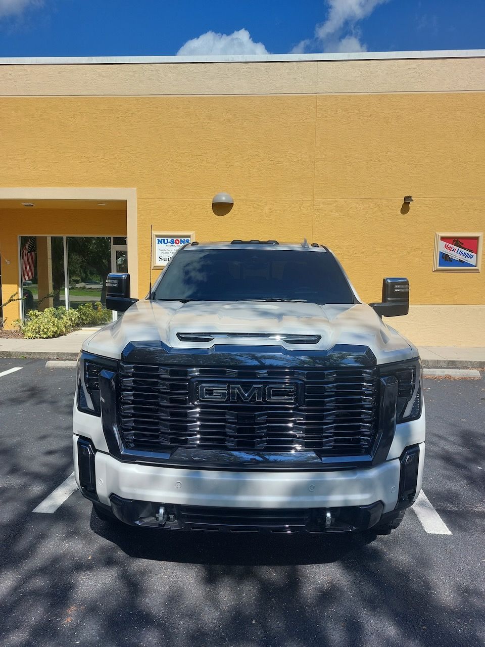 A white gmc truck is parked in front of a pepsi store