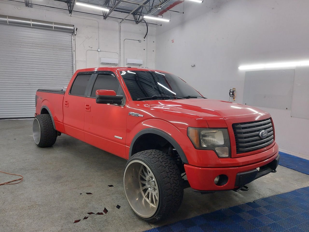 A red ford f150 truck is parked in a garage.