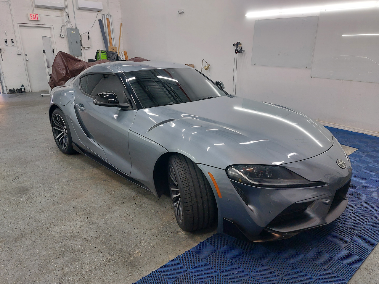 A gray toyota supra is parked in a garage.