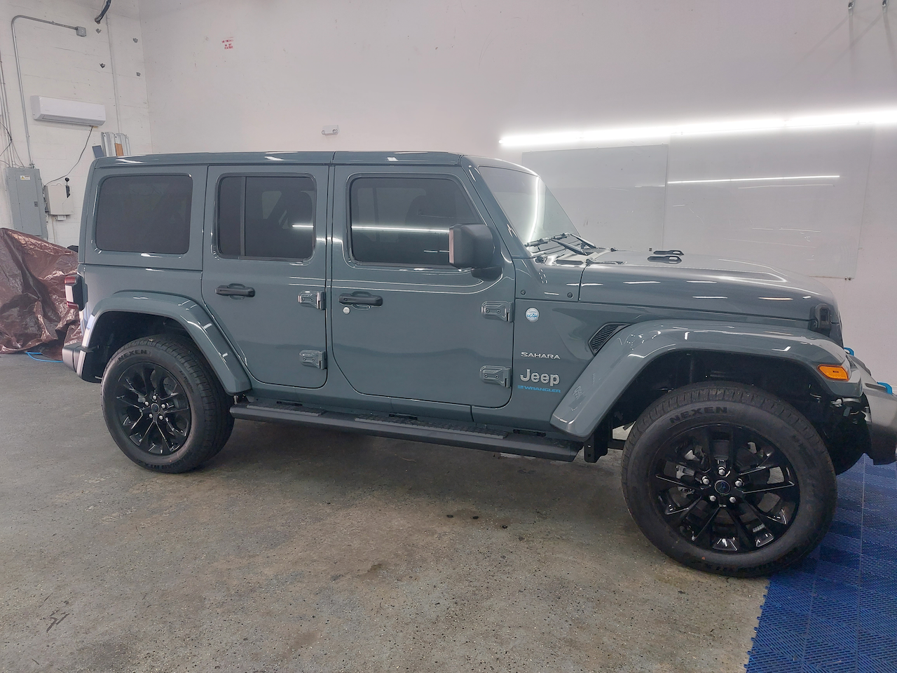 A gray jeep wrangler is parked in a garage.