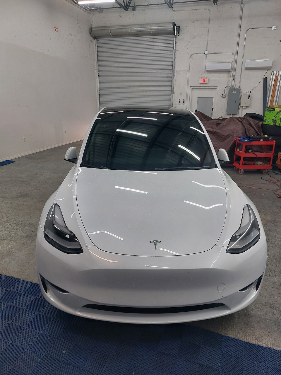 A white tesla model 3 is parked in a garage.