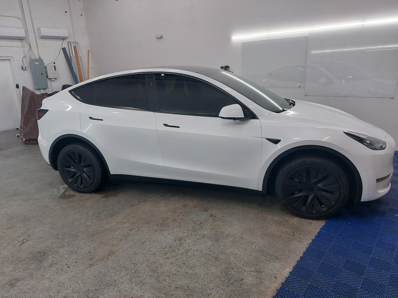 A white tesla model y is parked in a garage.