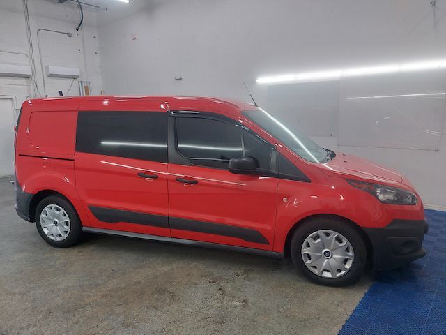 A red van is parked in a garage next to a white wall.