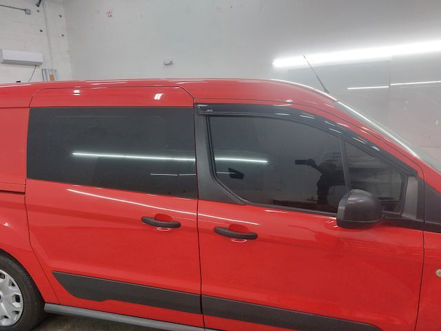 A red van with black windows is parked in a garage.
