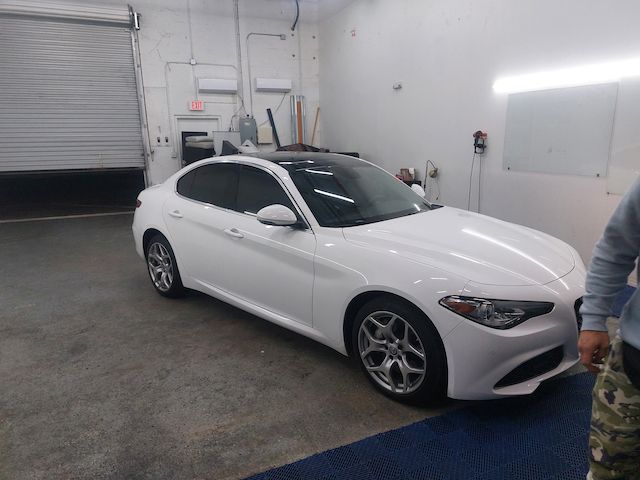 A man is standing next to a white car in a garage