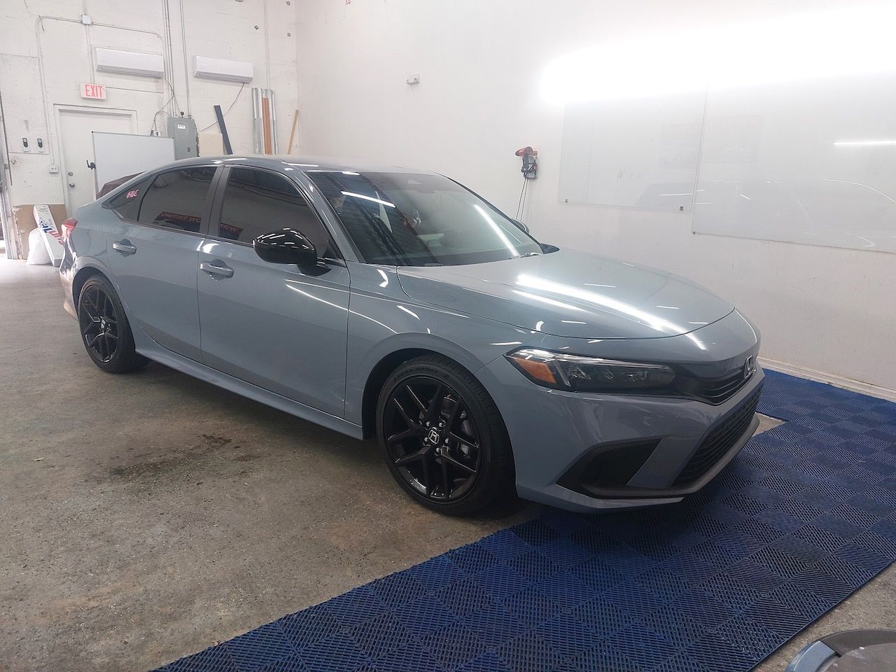 A gray honda civic is parked in a garage.