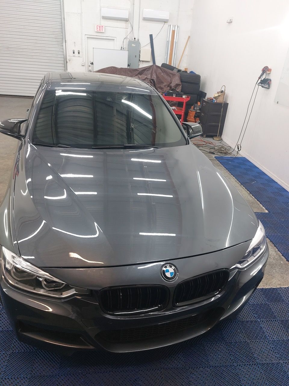 A gray bmw is parked in a garage.