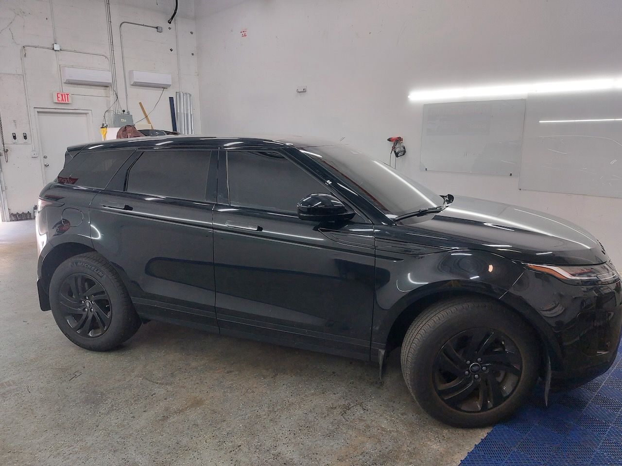 A black range rover evoque is parked in a garage.