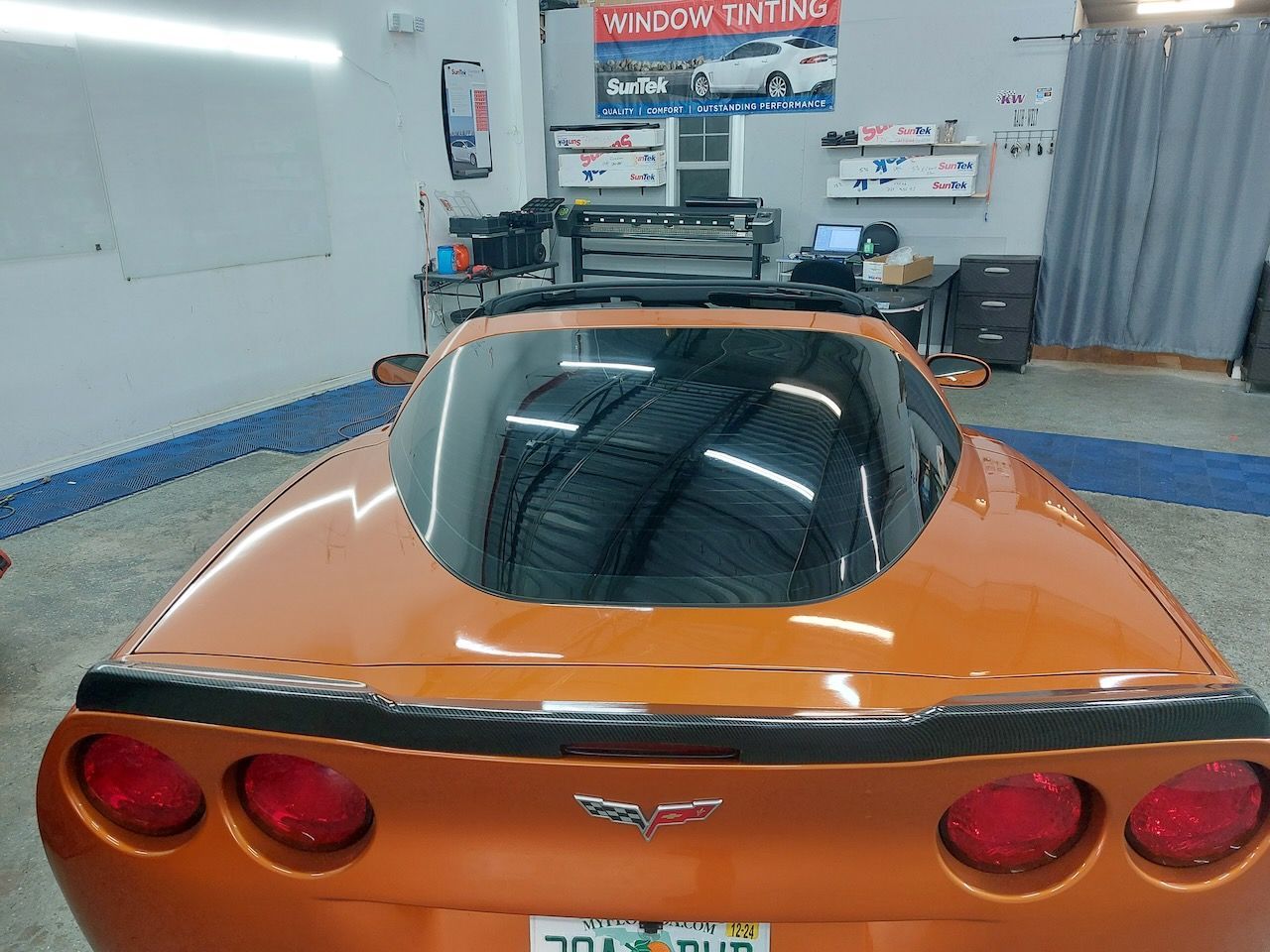 An orange sports car is parked in a garage with a sign that says ' xtreme detailing ' on it