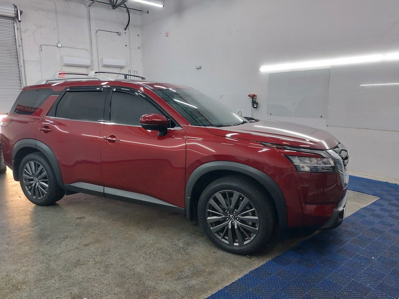 A red nissan pathfinder is parked in a garage.