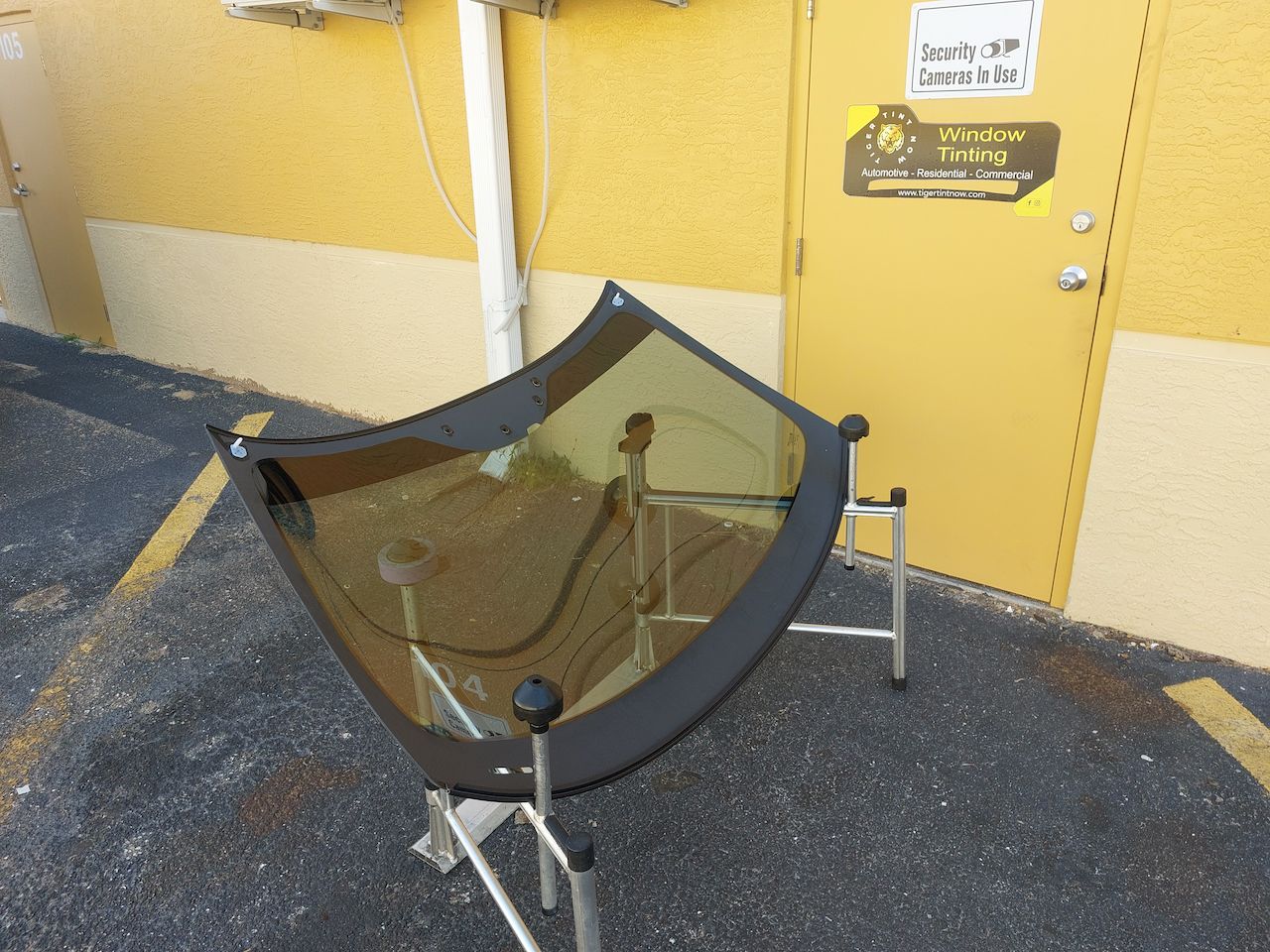 A windshield is sitting on a stand in front of a yellow door