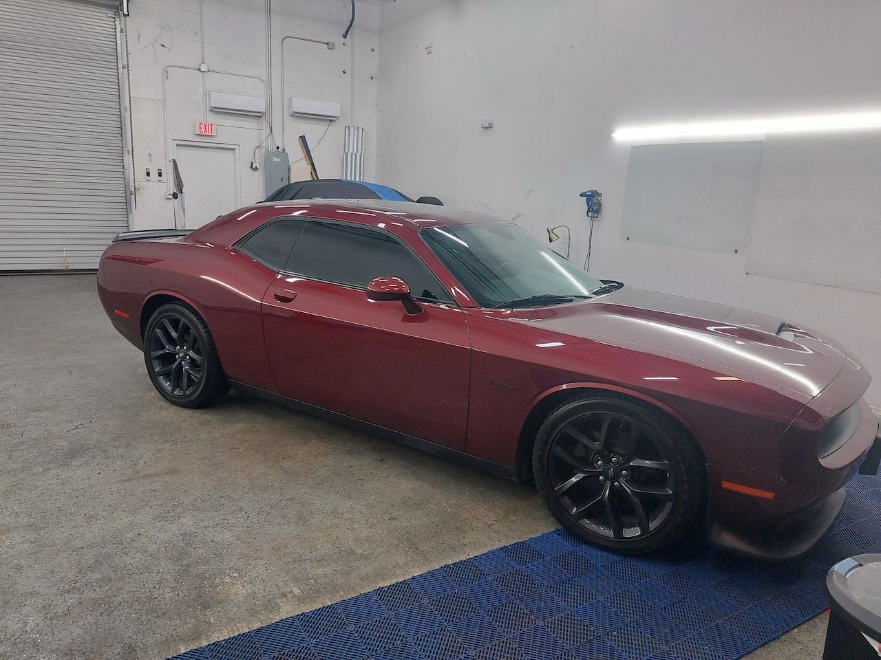 A red dodge challenger is parked in a garage.