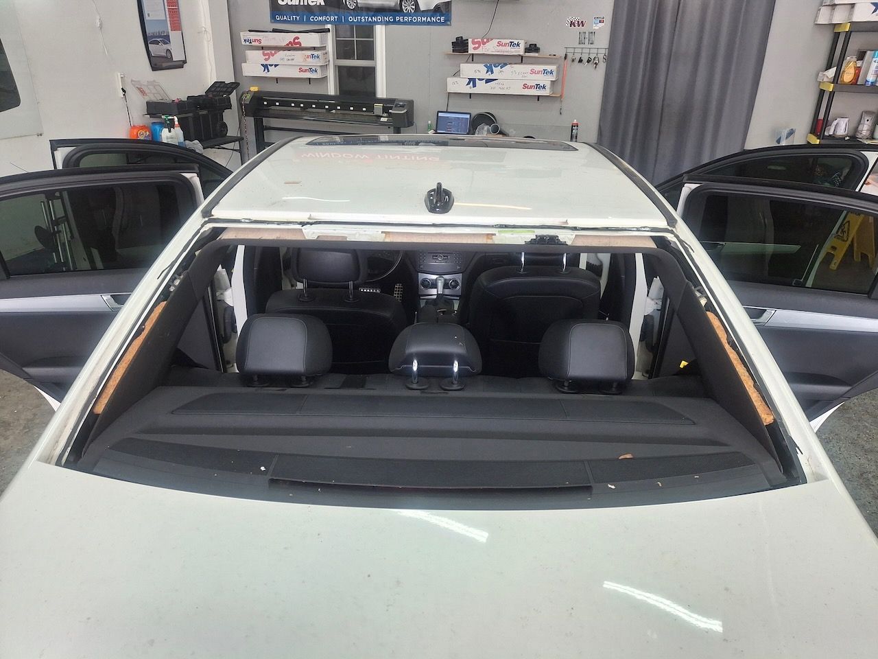 A white car with a broken windshield is sitting in a garage.